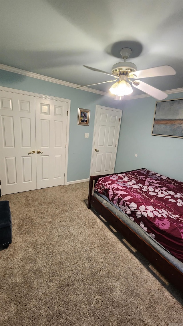 bedroom featuring carpet, a closet, ornamental molding, a ceiling fan, and baseboards