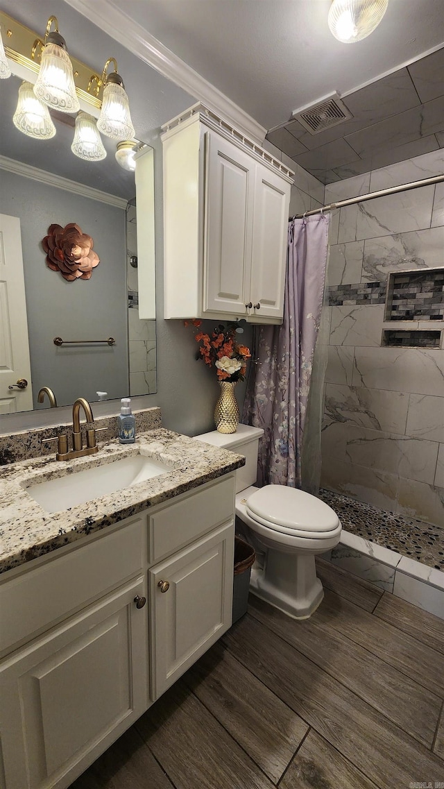 bathroom with visible vents, tiled shower, toilet, crown molding, and vanity