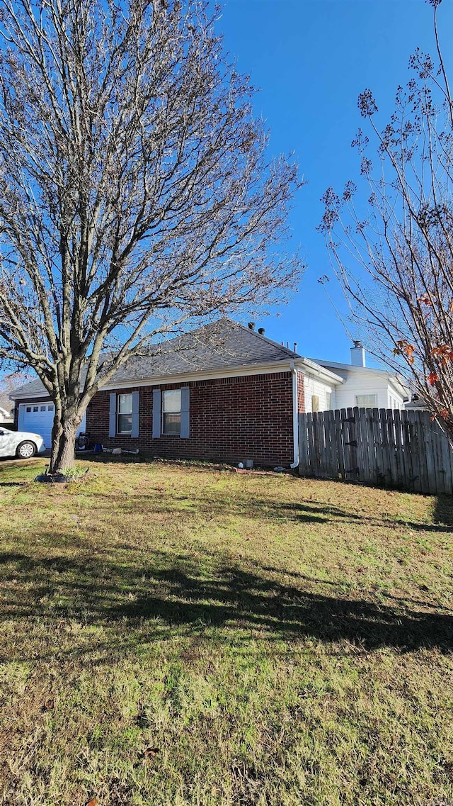 exterior space featuring a yard, brick siding, and fence