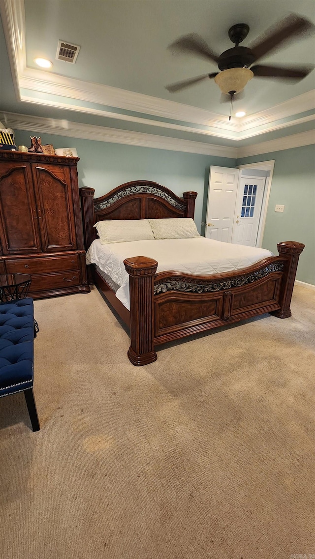 bedroom with carpet floors, visible vents, a tray ceiling, and a ceiling fan