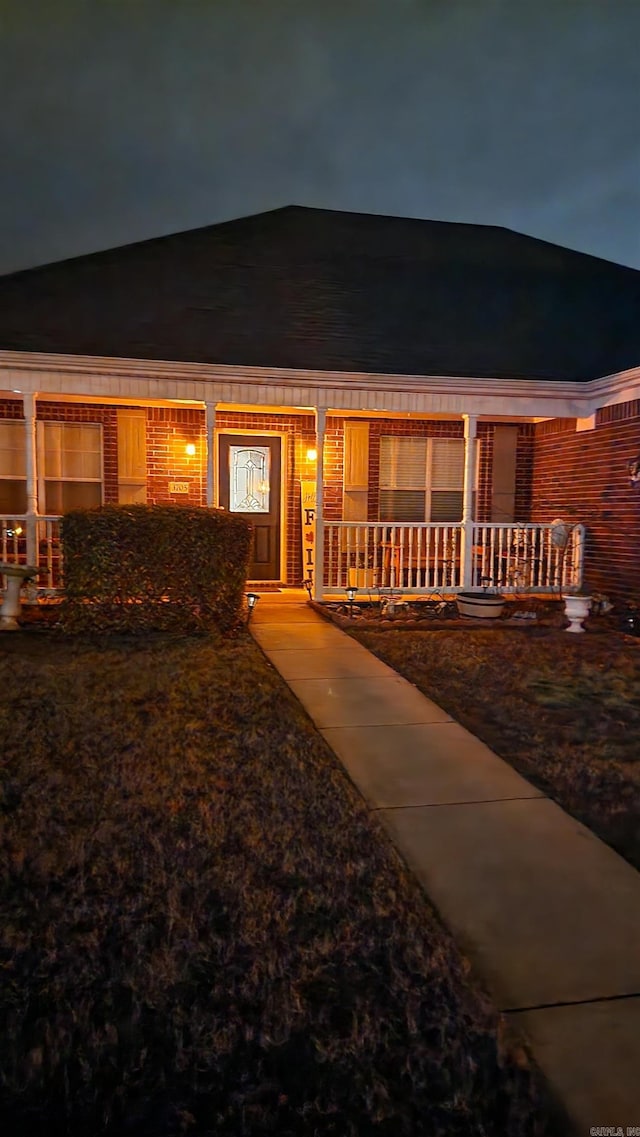 exterior entry at night with covered porch and brick siding