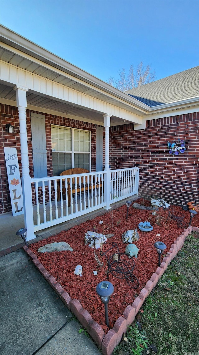 view of property exterior featuring covered porch and brick siding