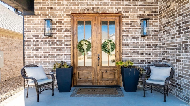 doorway to property featuring french doors, brick siding, and a patio area