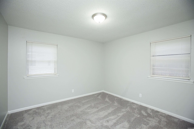 carpeted empty room featuring baseboards and a textured ceiling