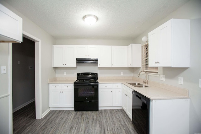 kitchen featuring white cabinets, light wood-style floors, under cabinet range hood, black appliances, and a sink