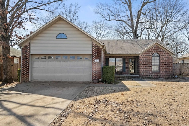 ranch-style home with concrete driveway, roof with shingles, an attached garage, fence, and brick siding