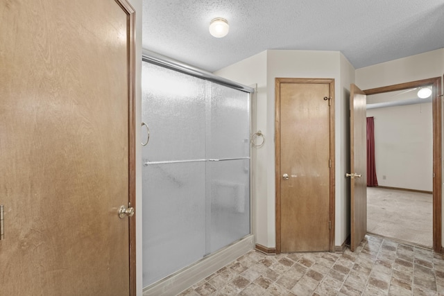 bathroom with a shower stall, baseboards, and a textured ceiling