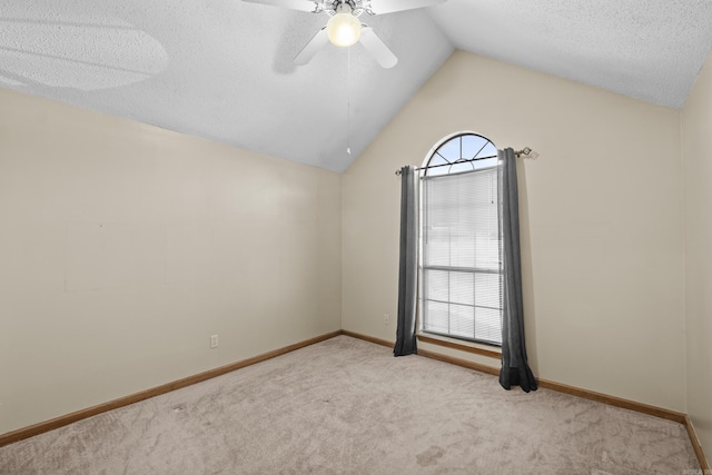 empty room with a textured ceiling, a ceiling fan, baseboards, vaulted ceiling, and carpet