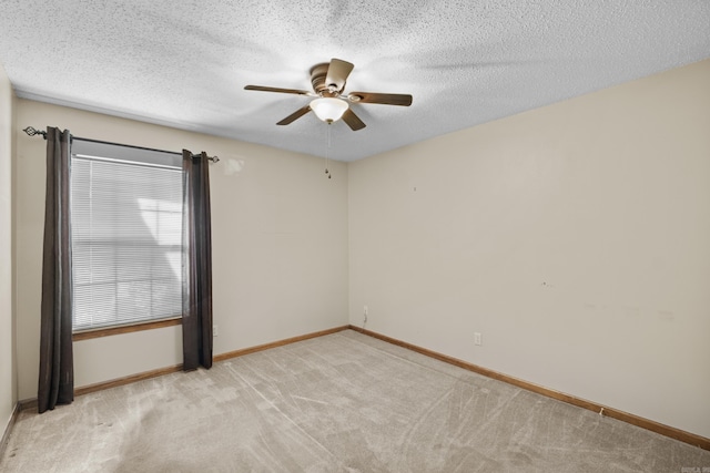 spare room with light carpet, a textured ceiling, a ceiling fan, and baseboards