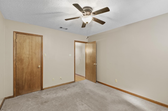 unfurnished bedroom with baseboards, visible vents, a ceiling fan, light colored carpet, and a textured ceiling