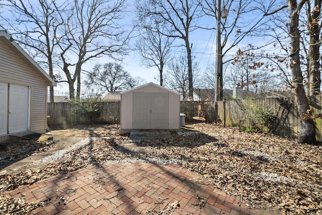 view of yard with a patio area, a fenced backyard, an outdoor structure, and a storage unit