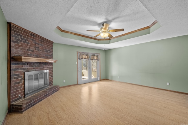 unfurnished living room featuring crown molding, a raised ceiling, a fireplace, and wood finished floors