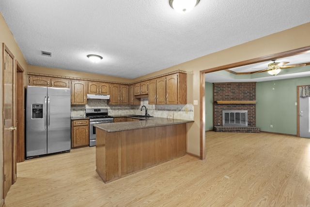 kitchen with visible vents, appliances with stainless steel finishes, a sink, a peninsula, and under cabinet range hood