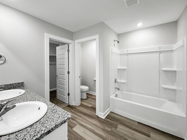 full bath featuring toilet, visible vents, a sink, and wood finished floors