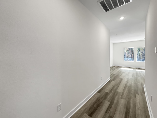 hall with dark wood-style flooring, visible vents, and baseboards