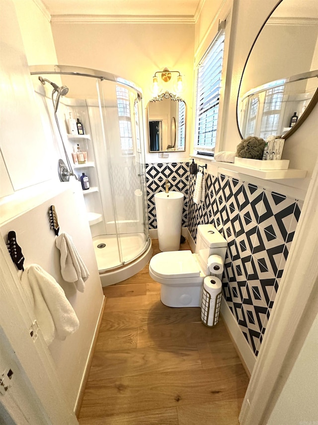 bathroom featuring a stall shower, toilet, wood finished floors, crown molding, and a healthy amount of sunlight