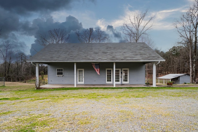 view of front of home with french doors, a patio area, a front lawn, and roof with shingles