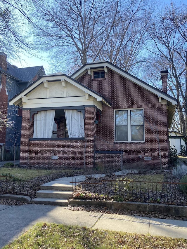 bungalow-style house with brick siding and a chimney