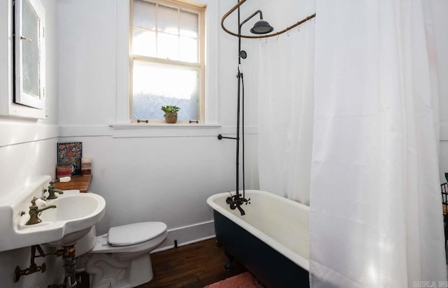 bathroom featuring a shower with shower curtain, toilet, wood finished floors, a freestanding tub, and a sink