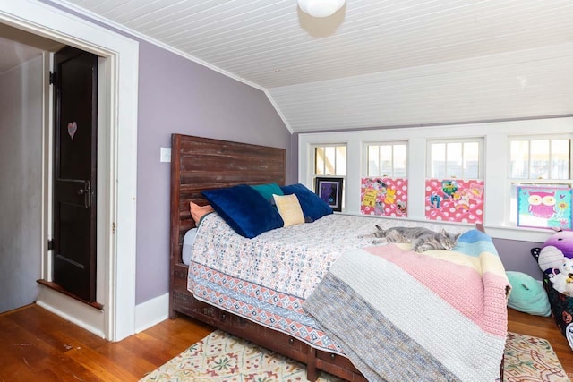 bedroom with lofted ceiling, crown molding, baseboards, and wood finished floors