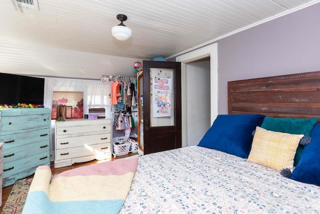 bedroom with a closet, visible vents, crown molding, and wood finished floors