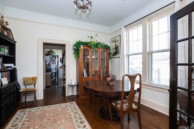 dining room with dark wood-type flooring, a wealth of natural light, and a notable chandelier