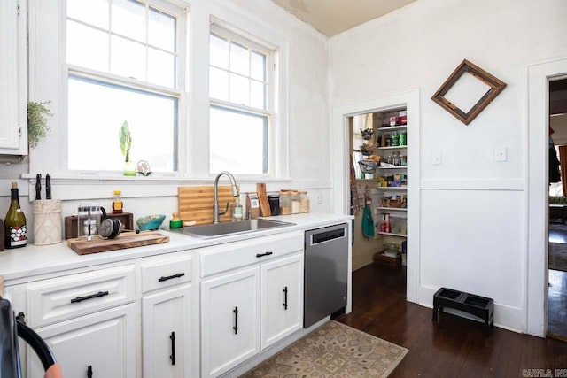 kitchen featuring dark wood finished floors, dishwasher, light countertops, white cabinetry, and a sink