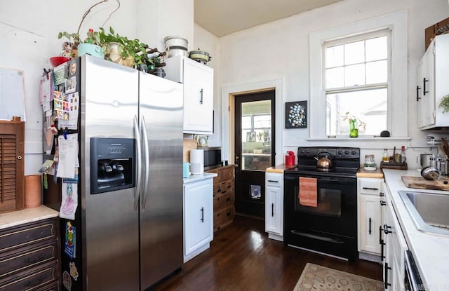 kitchen featuring stainless steel fridge, white cabinetry, light countertops, and black range with electric stovetop