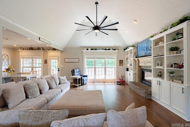 living room featuring a healthy amount of sunlight, ornamental molding, dark wood finished floors, and a glass covered fireplace