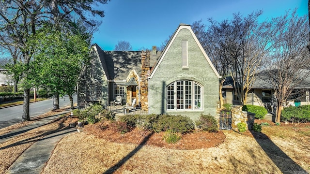 tudor house featuring brick siding and a chimney