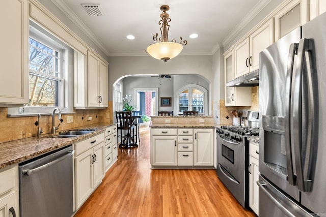 kitchen with visible vents, arched walkways, stainless steel appliances, under cabinet range hood, and a sink