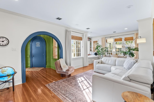 living room with visible vents, crown molding, arched walkways, and wood finished floors