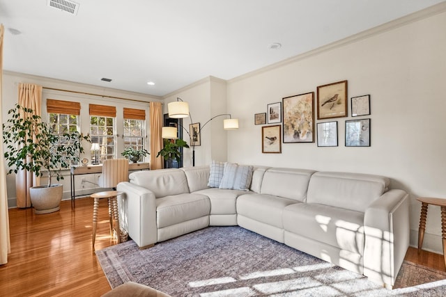 living area with ornamental molding, recessed lighting, visible vents, and wood finished floors