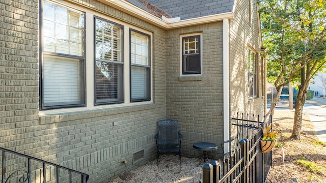 view of side of home featuring brick siding, crawl space, and a shingled roof