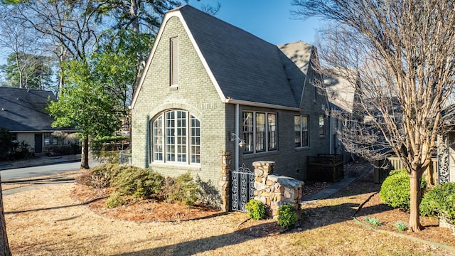 view of home's exterior featuring roof with shingles and brick siding