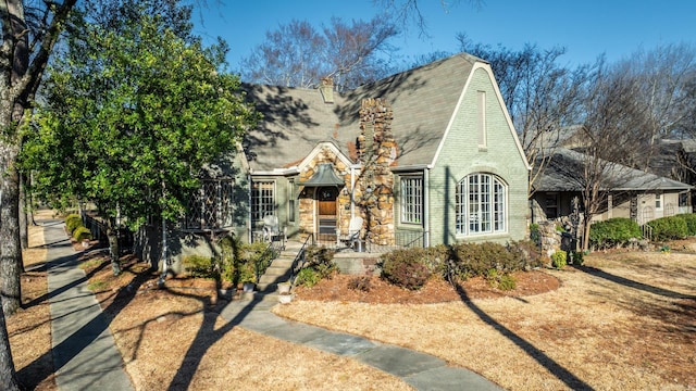 tudor house with brick siding and a shingled roof