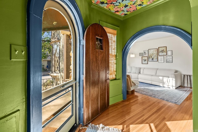 interior space with arched walkways, wood finished floors, a wealth of natural light, and crown molding