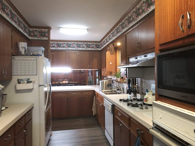 kitchen with under cabinet range hood, white appliances, wallpapered walls, and light countertops