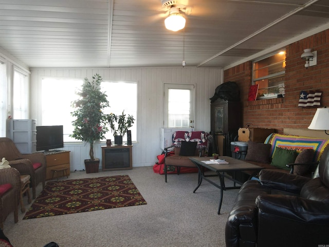 carpeted living room with a wealth of natural light and brick wall