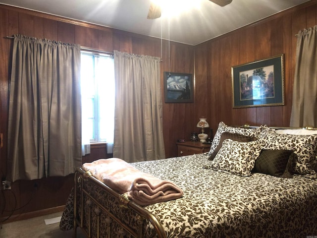 bedroom featuring wooden walls, a ceiling fan, and carpet