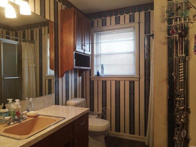 bathroom featuring curtained shower, wallpapered walls, vanity, and toilet