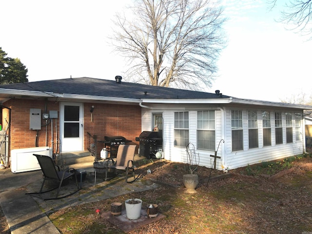 rear view of house featuring brick siding and a patio area