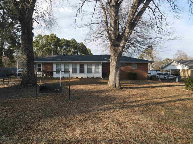 back of house featuring brick siding, a lawn, and fence