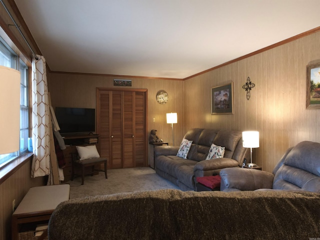 living room featuring a healthy amount of sunlight, ornamental molding, carpet flooring, and wood walls