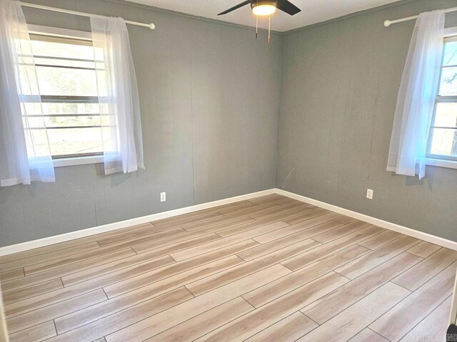 empty room featuring light wood-style floors, baseboards, and a ceiling fan