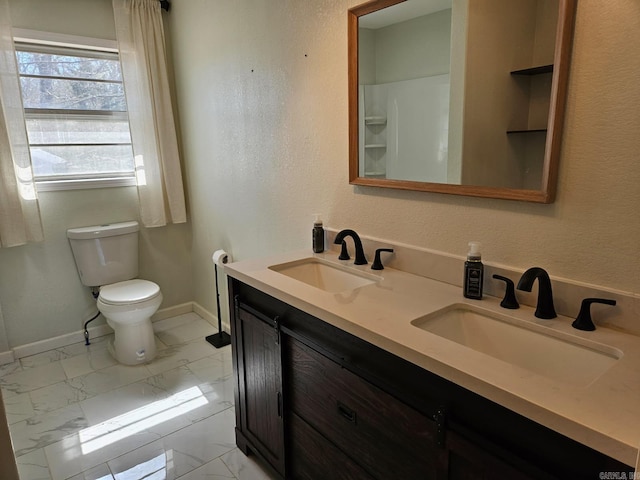 bathroom with toilet, marble finish floor, and a sink