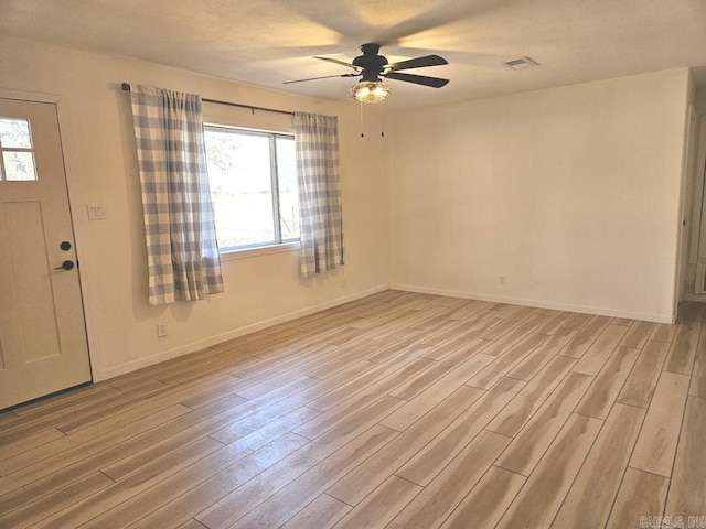 unfurnished room with light wood-style flooring, visible vents, baseboards, and ceiling fan