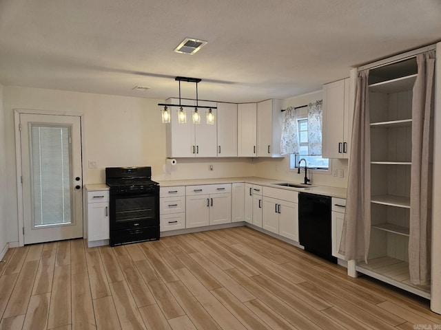 kitchen featuring a sink, visible vents, white cabinetry, light wood-type flooring, and black appliances