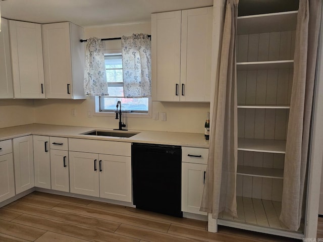 kitchen with black dishwasher, white cabinets, and a sink