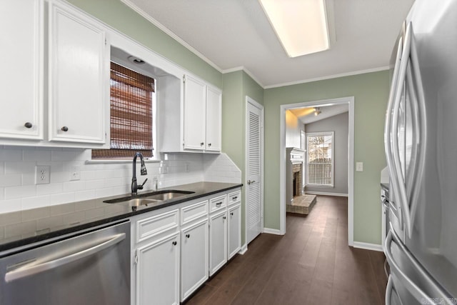 kitchen with decorative backsplash, dark wood finished floors, appliances with stainless steel finishes, white cabinetry, and a sink